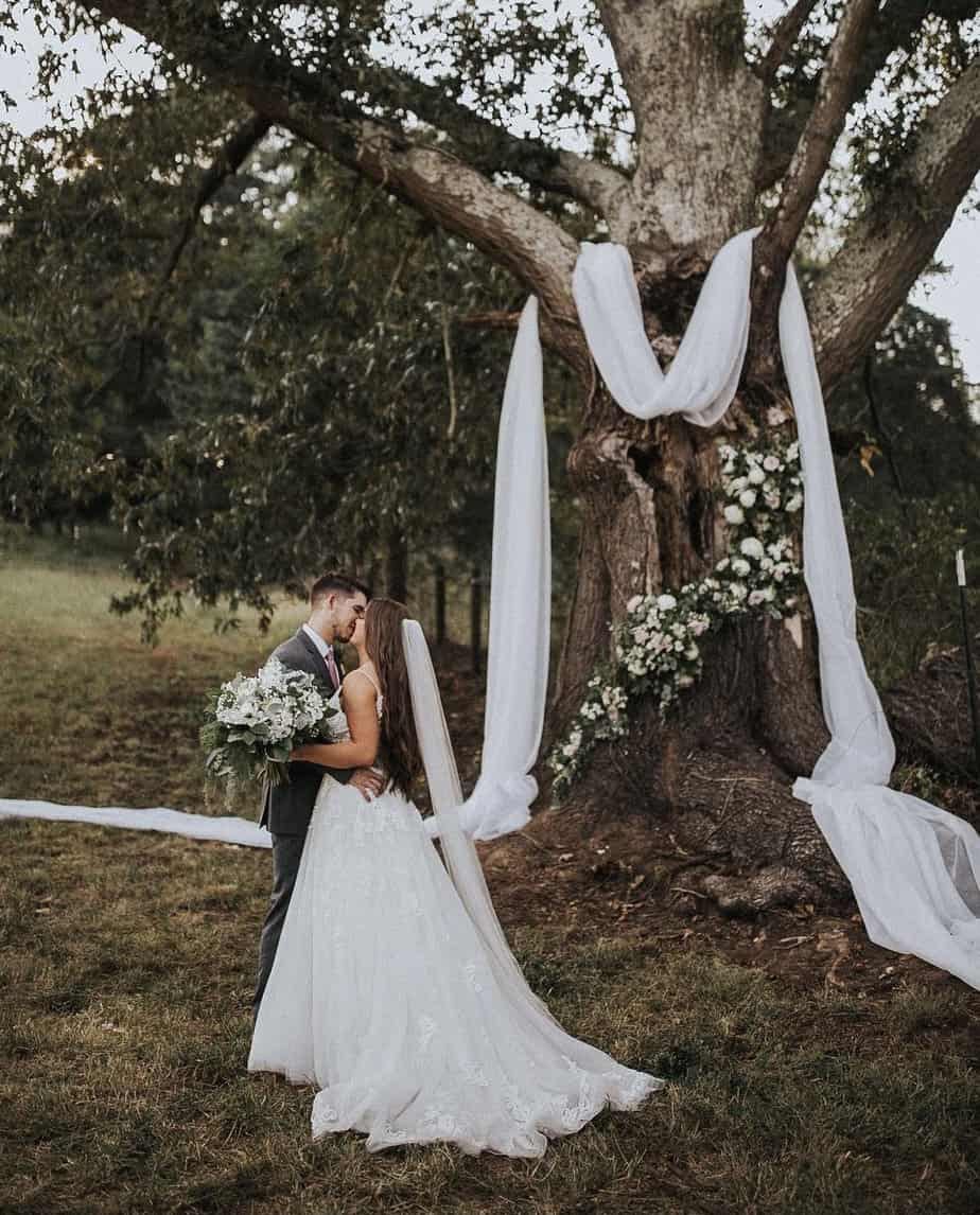A bride beneath the Big Oak Tree draped in white fabric and florals